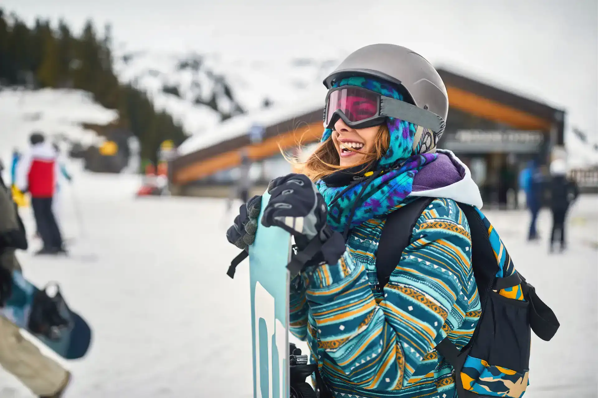 woman holding a snowboard while wearing ski clothing in the snow