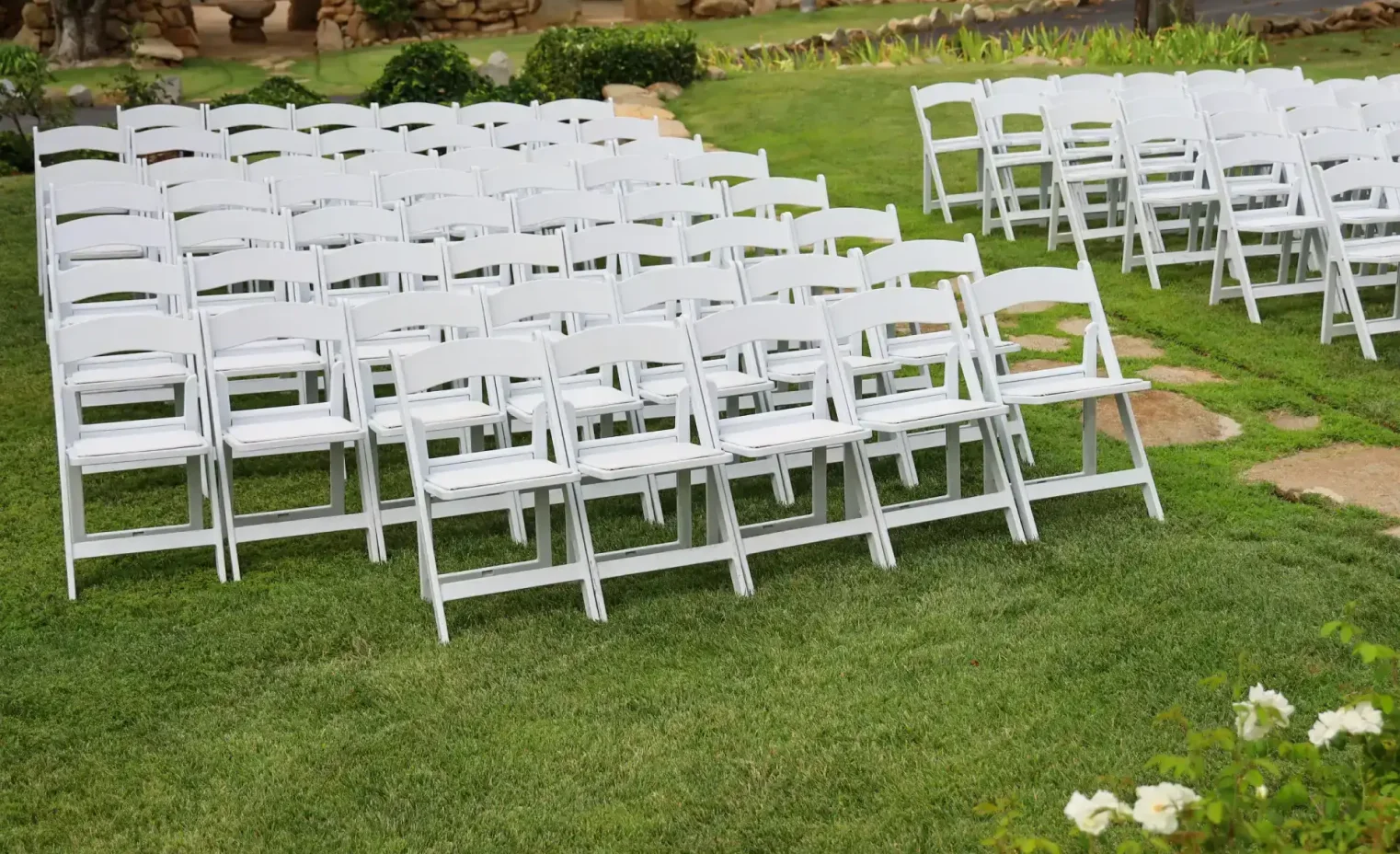 white folding chairs set up for an outdoor party.webp