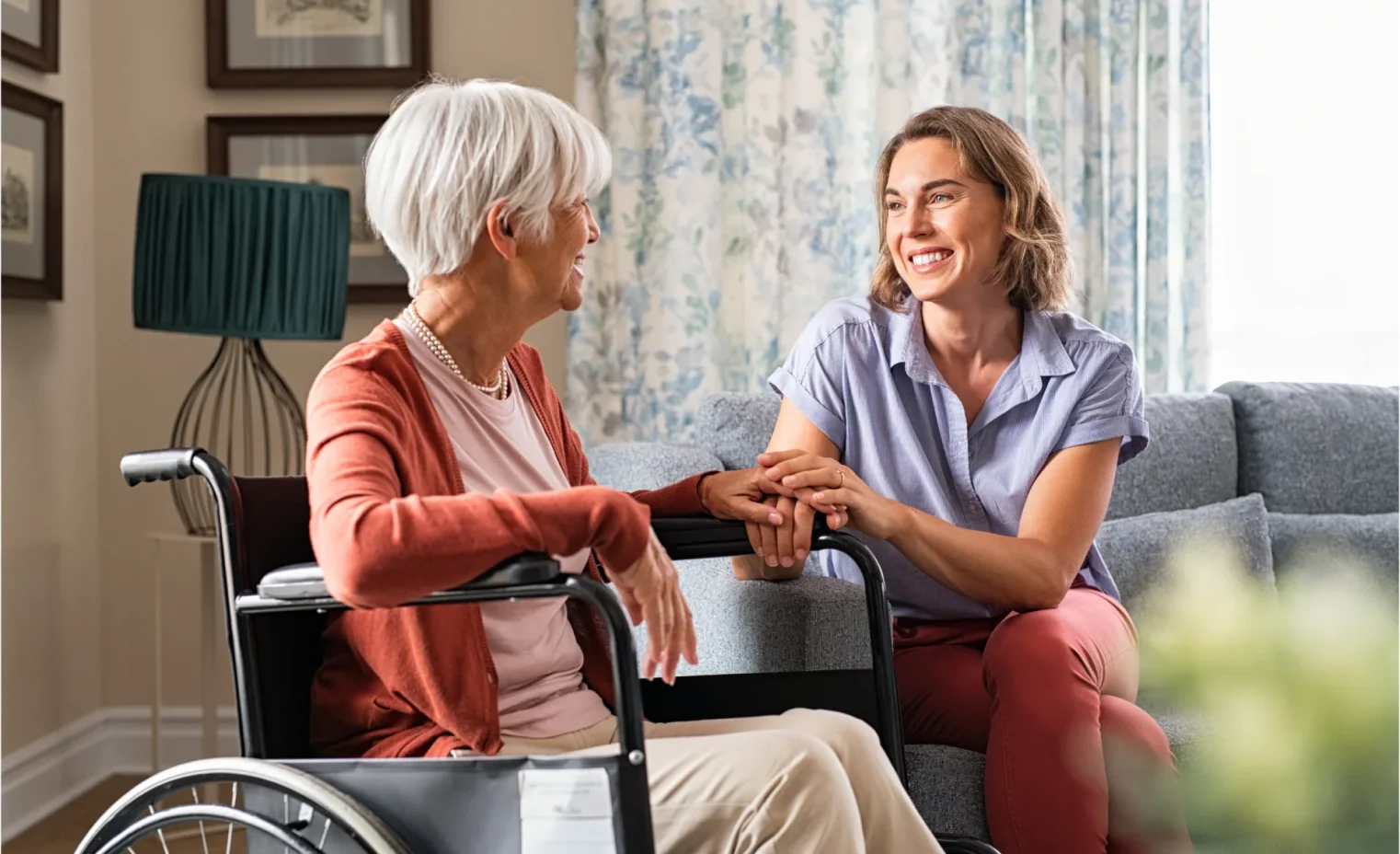 a nurse sits with an elderly woman in a wheelchair in a brightly lit care home.webp