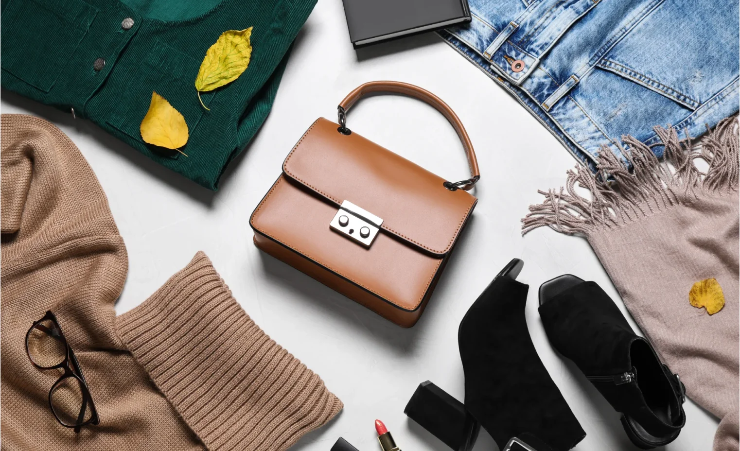 designer leather handbag, and other luxury goods arranged on white table as part of a luxury accessories display.webp