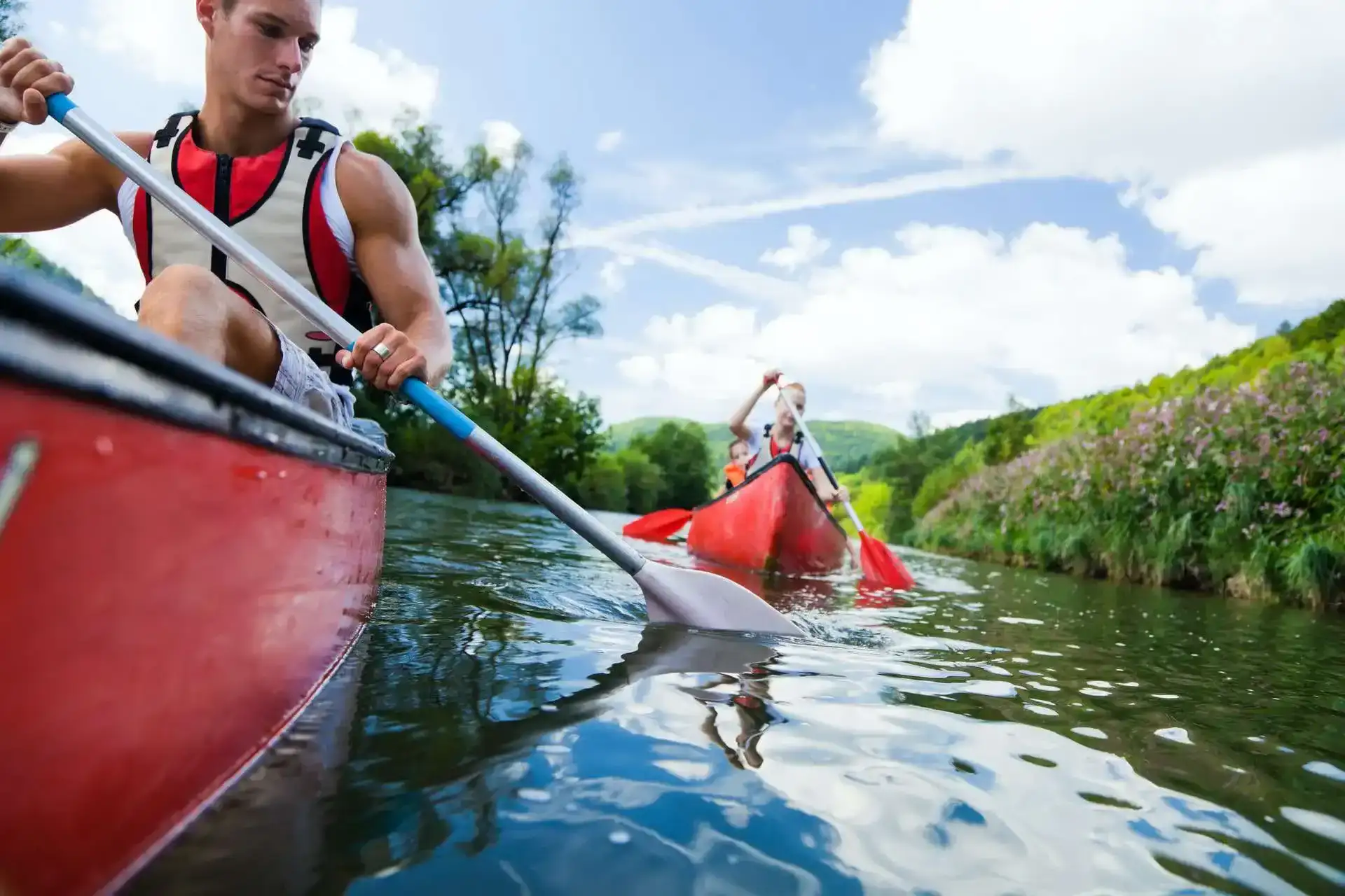 two orange kayaks with a couple paddling them on a calm lake.webp