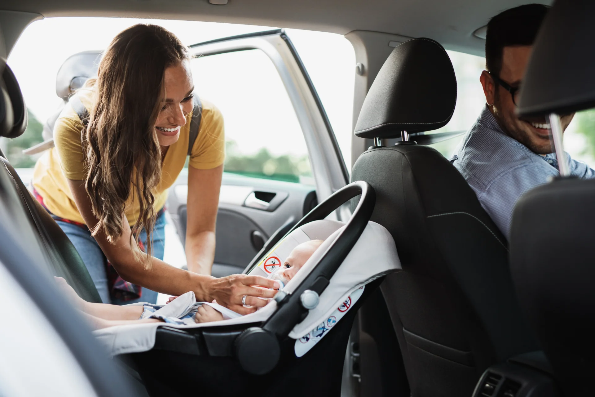 A woman putting her baby in a car seat